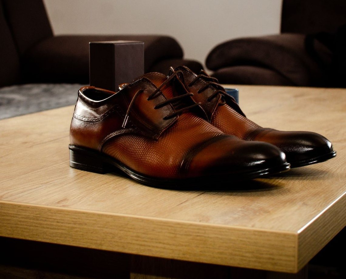 Polished brown cap-toe dress shoes on a wooden table